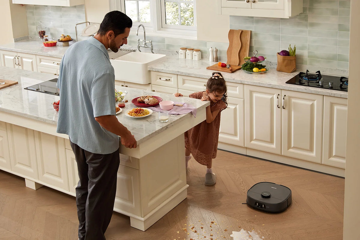 Un parent et un enfant regardant un robot aspirateur Eureka nettoyer le salon