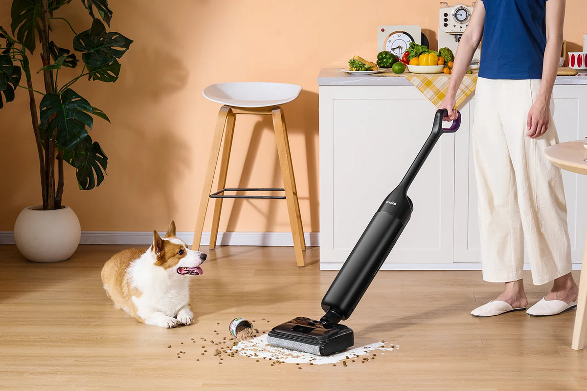 Une famille et un épagneul dans une cuisine lumineuse avec un aspirateur robot Eureka à proximité