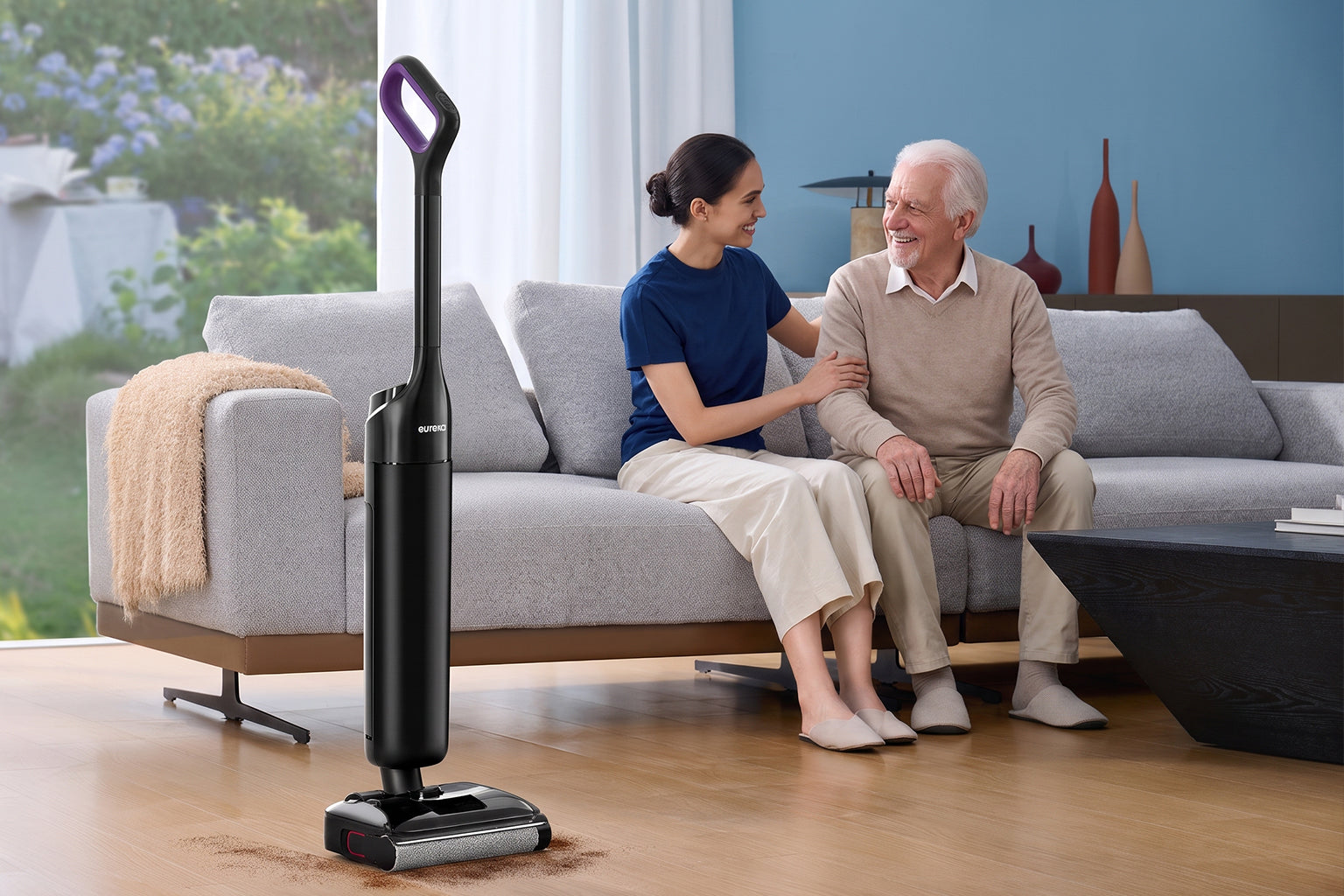 Adulte rendant visite à un parent âgé pendant qu'un robot aspirateur Eureka s'occupe de la maison